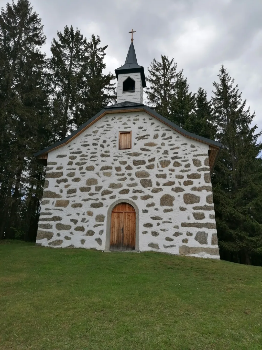 Kleine Kapelle aus Naturstein zwischen Fichten