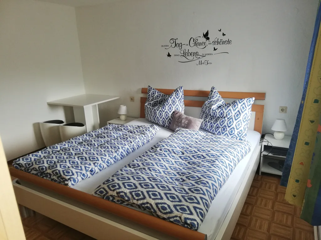 Doppelzimmer mit hellem Holzbett, Nachtkästchen und Schreibtisch